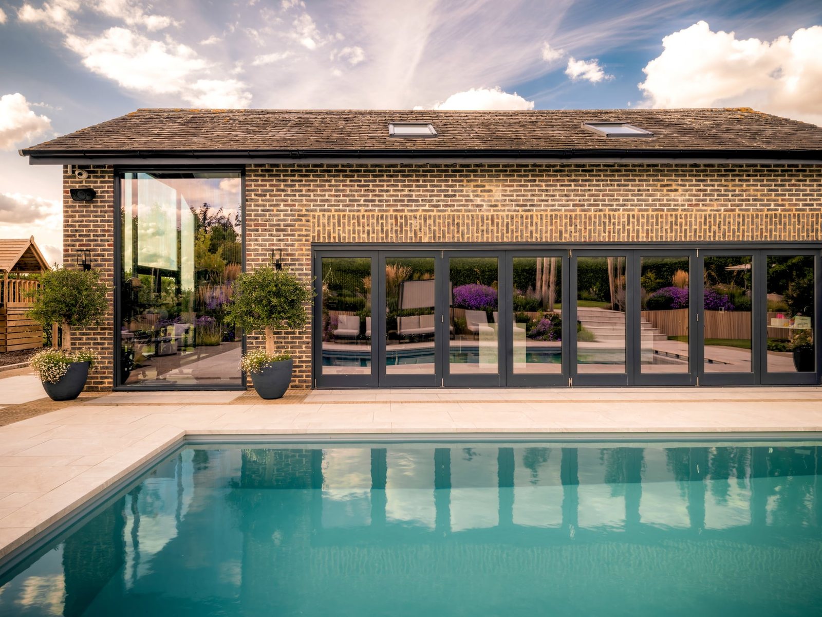 Poolhouse elevation in brick with folding glazed doors opening onto the pool terrace